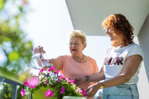Une bénéficiaire en train d'arroser ses fleurs avec son proche aidant